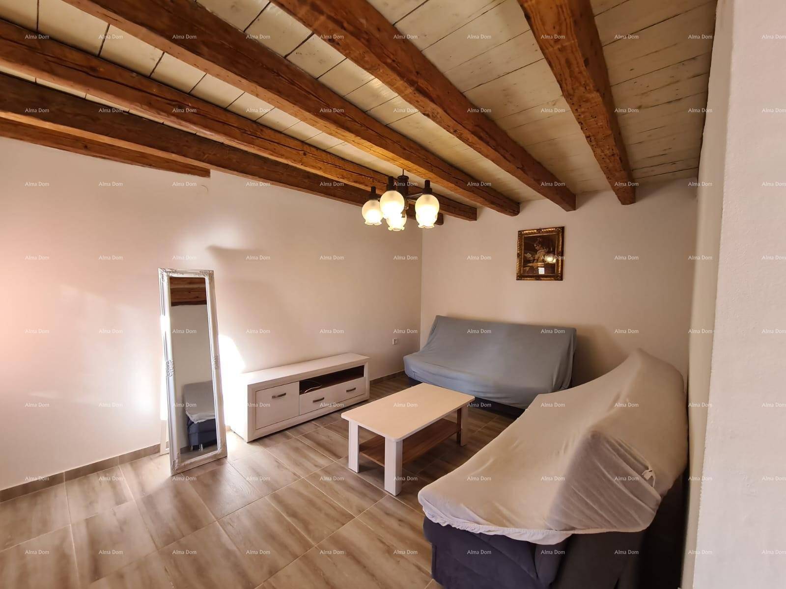 Wohnzimmer mit Sofa, TV-Möbel und großem Spiegel unter rustikaler Holzbalkendecke.