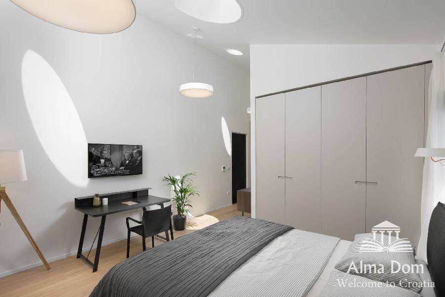 Schlafzimmer mit integrierten Kleiderschränken, Schreibtisch und modernem Beleuchtungskonzept.
