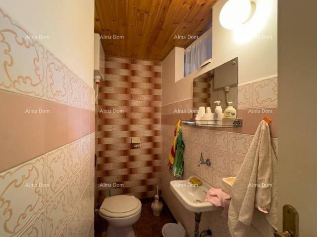 Kleines Gäste-WC mit gemusterten Fliesen, Toilette und Waschbecken, unter einer Holzdecke.