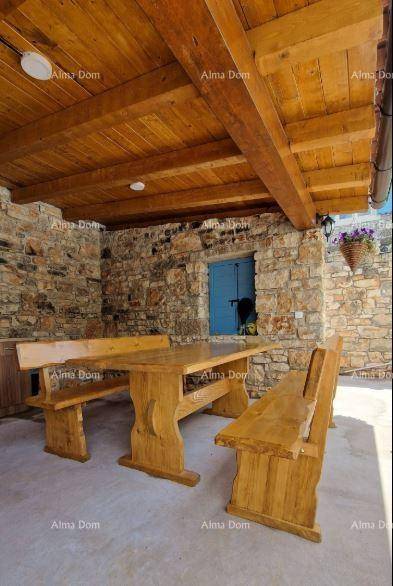 Gemütlicher Essbereich im Freien mit massivem Holztisch und Bänken unter einer Holzdecke.