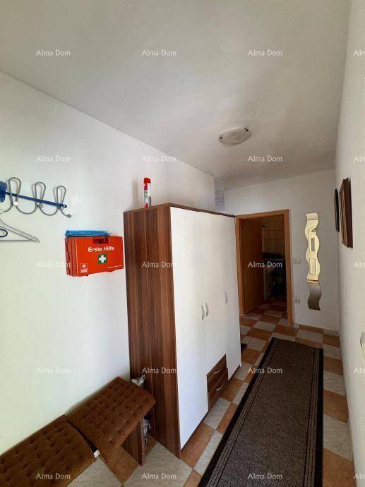Heller Flur mit Kleiderschrank, Sitzbank und gefliestem Boden, der zu weiteren Räumen führt.