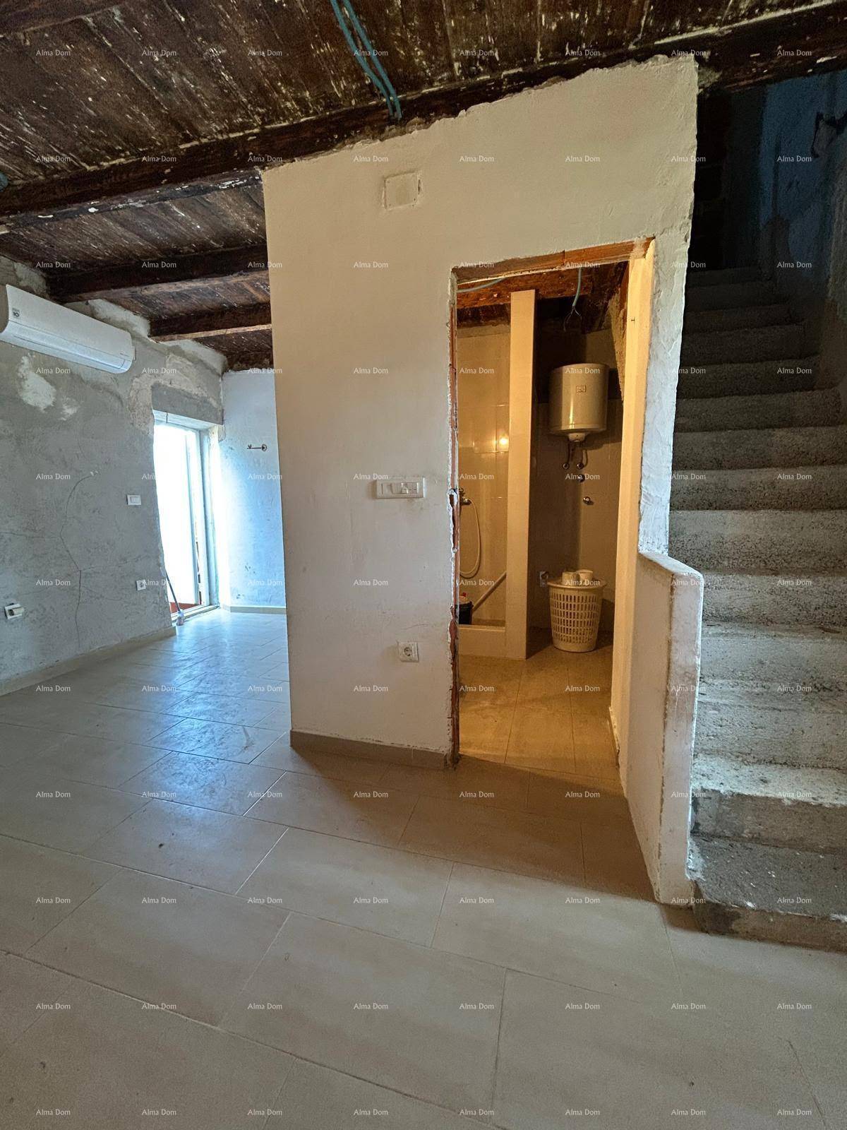 Flur im Rohbau mit Treppenaufgang, Fliesenboden und Blick in ein Badezimmer.
