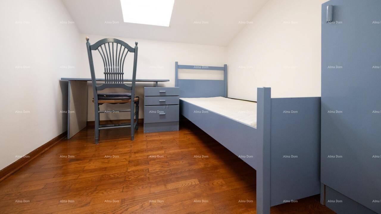 Kinderzimmer im Dachgeschoss mit blauem Bett, Schreibtisch und Dachfenster.
