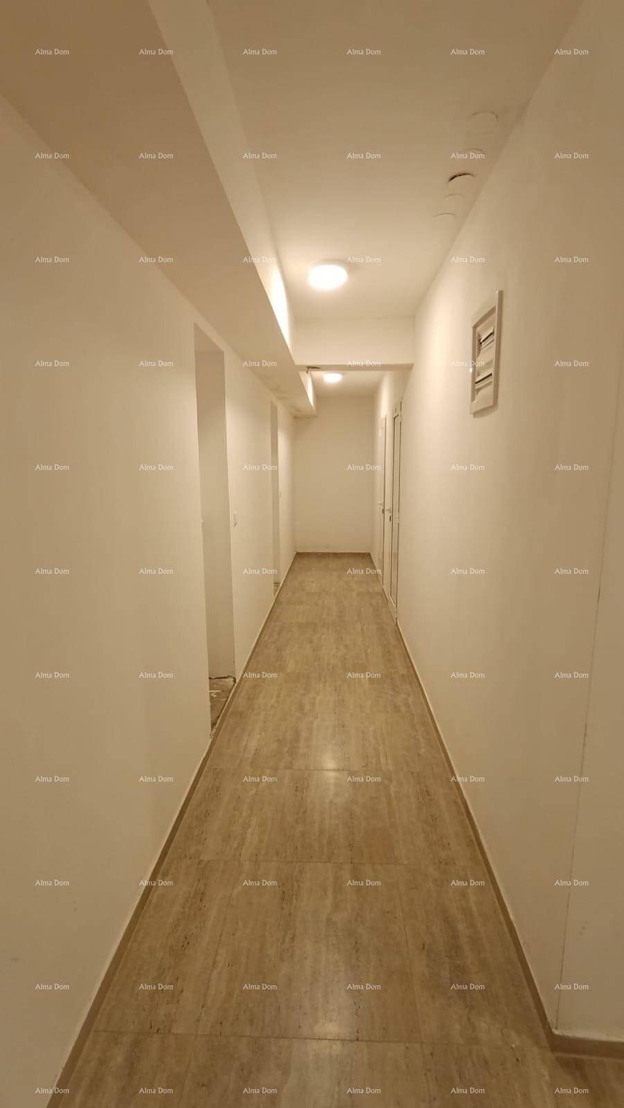 Langer, heller Flur mit Fliesenboden und schlichten weißen Wänden.