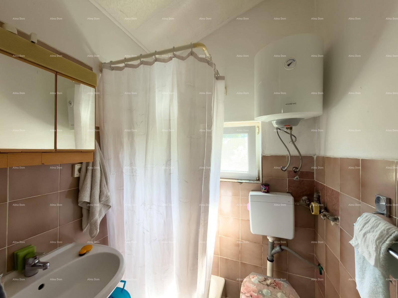 Funktionales Badezimmer mit Duschvorhang, Waschbecken, Toilette und einem Warmwasserboiler.