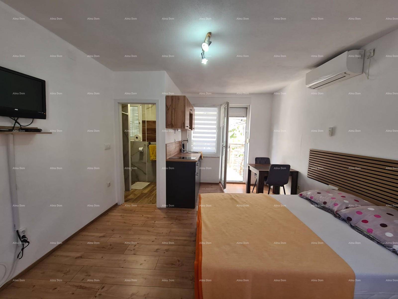 Helles Schlafzimmer mit Doppelbett, Küchenzeile und Esstisch, mit Holzboden.