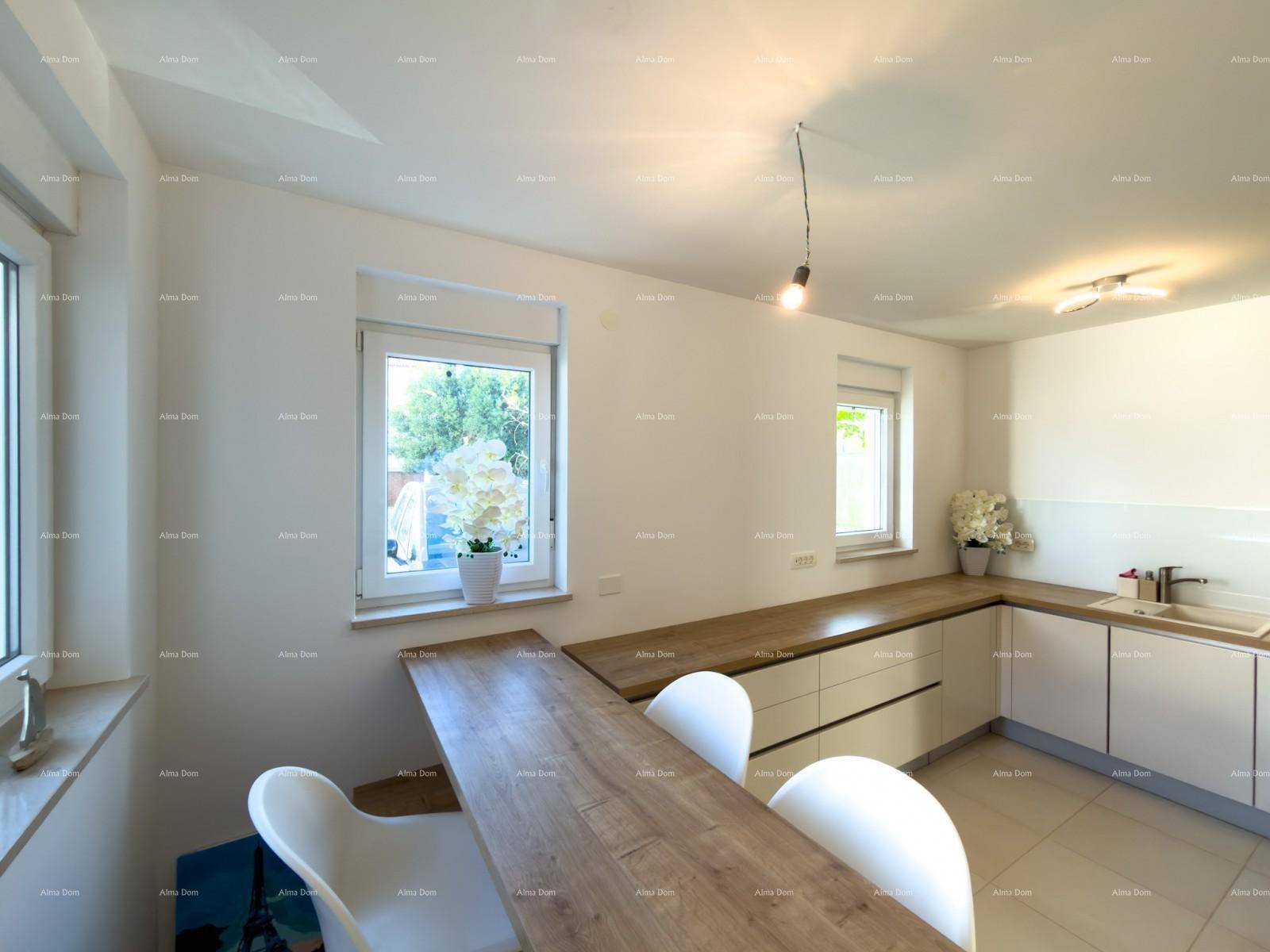 Moderne Küche mit Holzarbeitsplatten, weißen Schränken und Essbereich am Fenster.