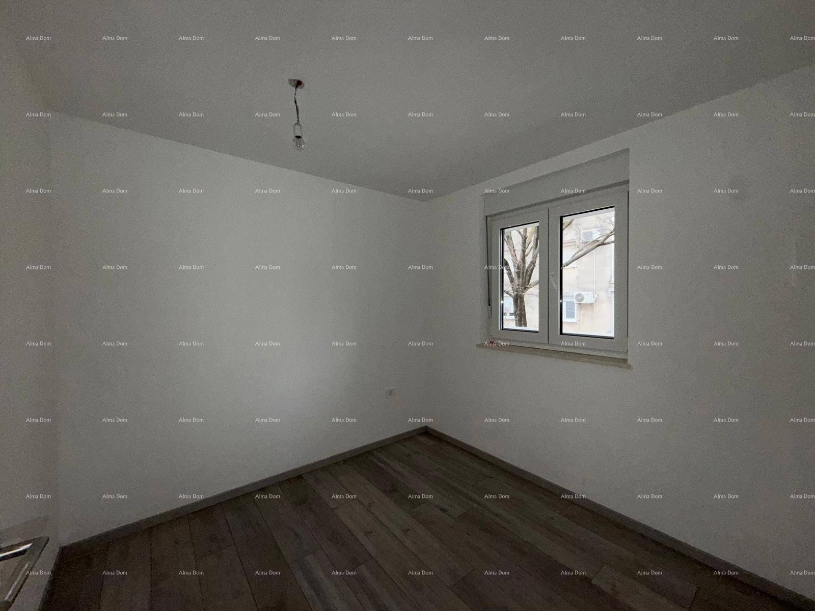 Leeres Schlafzimmer mit Holzboden und Fenster, das viel Tageslicht hereinlässt.
