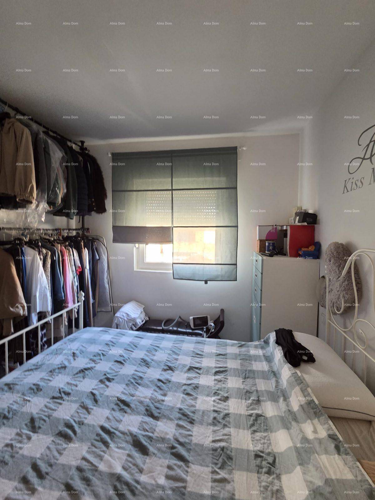 Schlafzimmer mit großem Bett, offener Kleiderstange und Fenster für natürliches Licht.