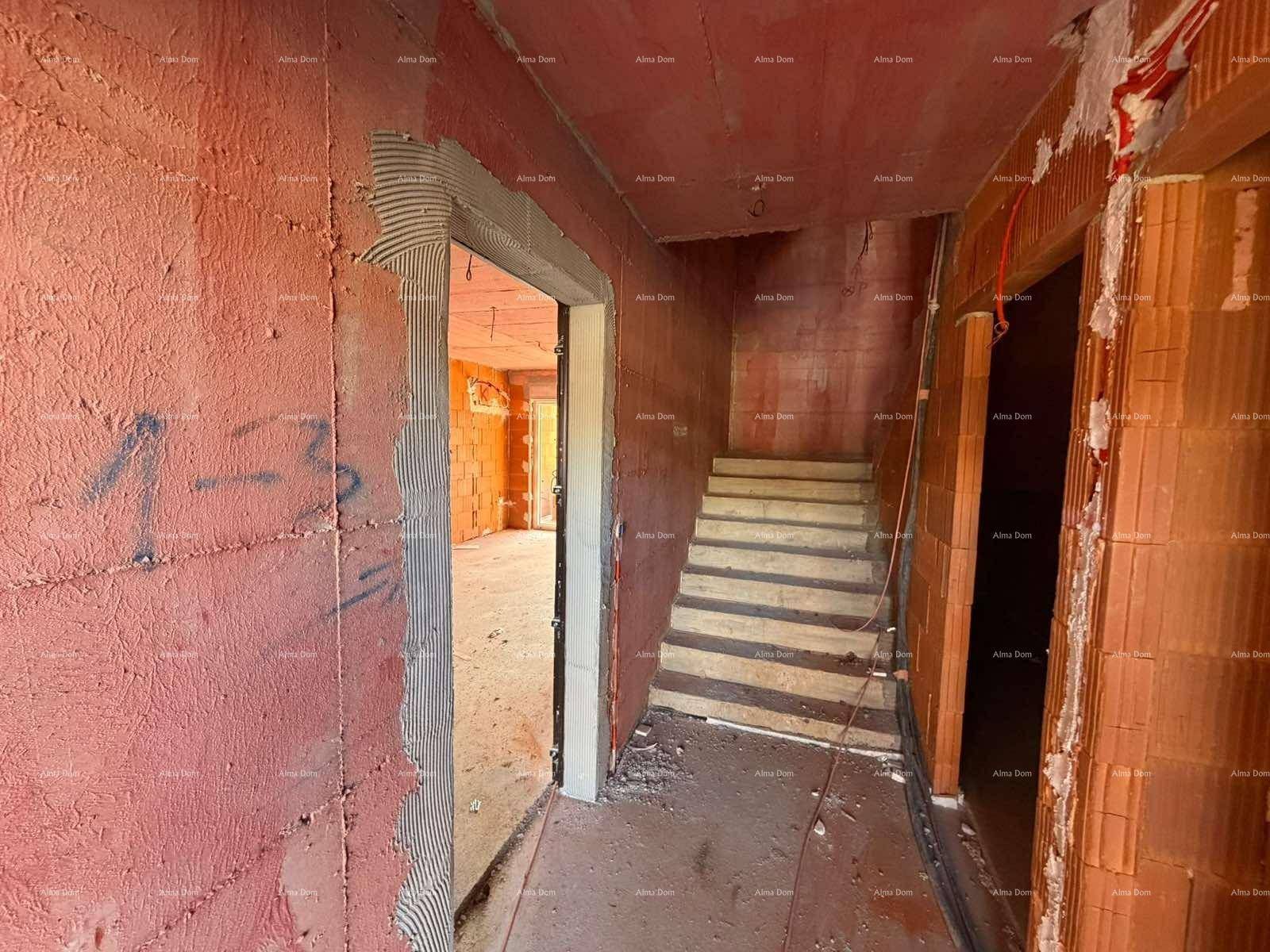 Treppenhaus und Flur im Rohbau mit sichtbaren Ziegelwänden und Treppenstufen.