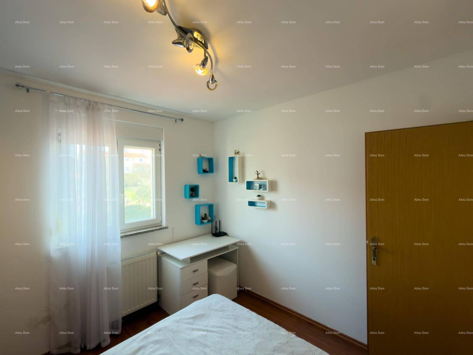 Helles Schlafzimmer mit Schreibtisch, Holzboden und Fenster mit Blick ins Freie.