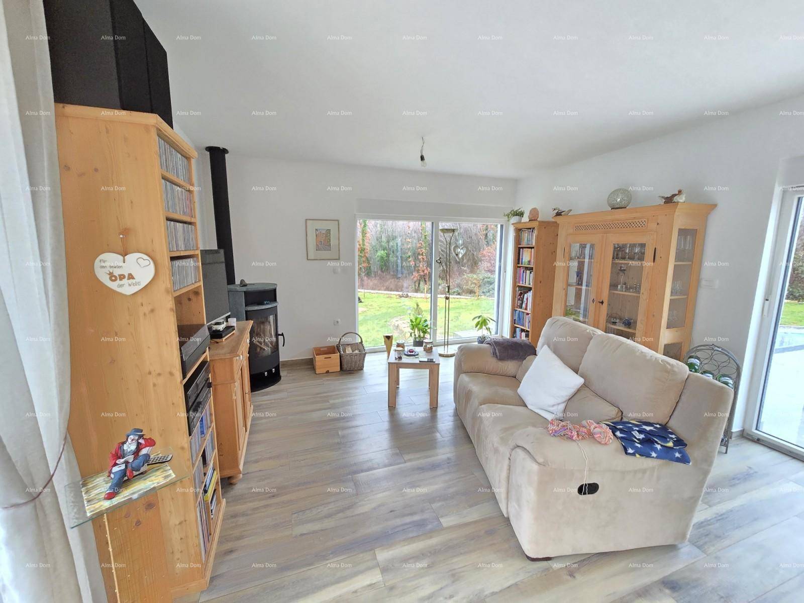 Gemütliches Wohnzimmer mit Holzofen, beigem Sofa und Blick ins Grüne.