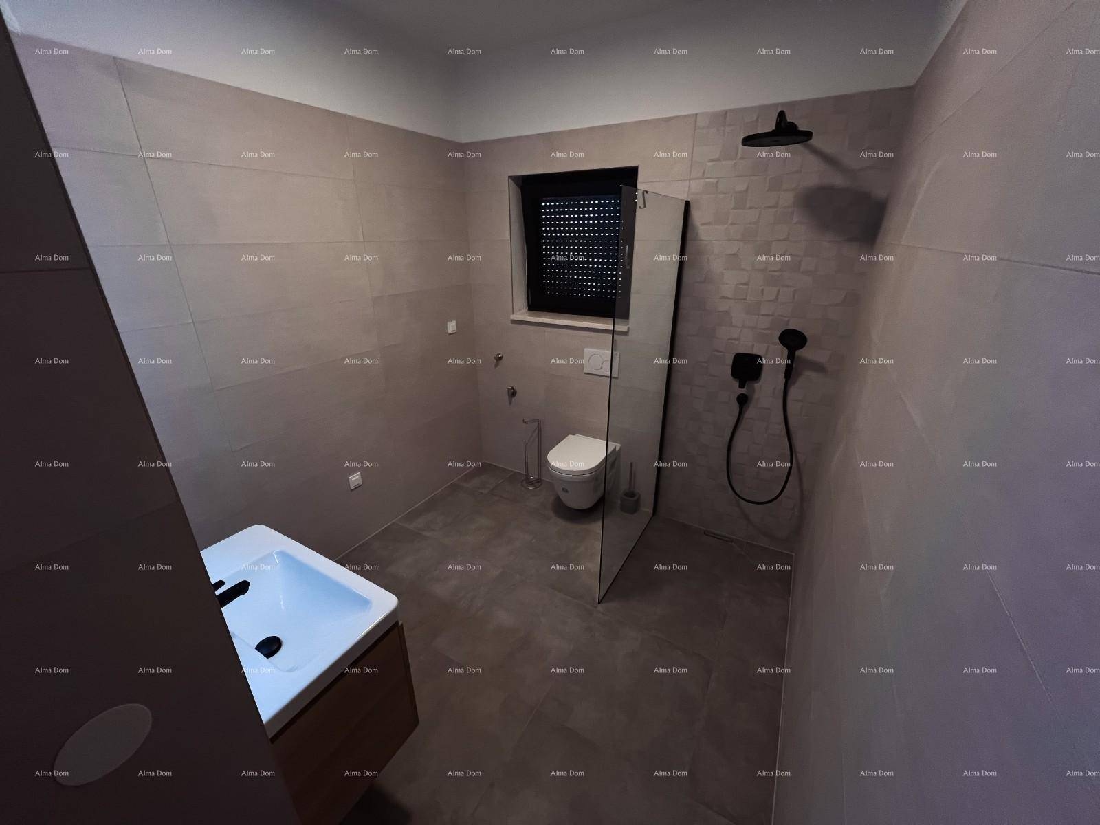 Geräumiges Badezimmer mit moderner Dusche, wandhängendem WC und eleganten grauen Fliesen, die ein sauberes Design betonen.