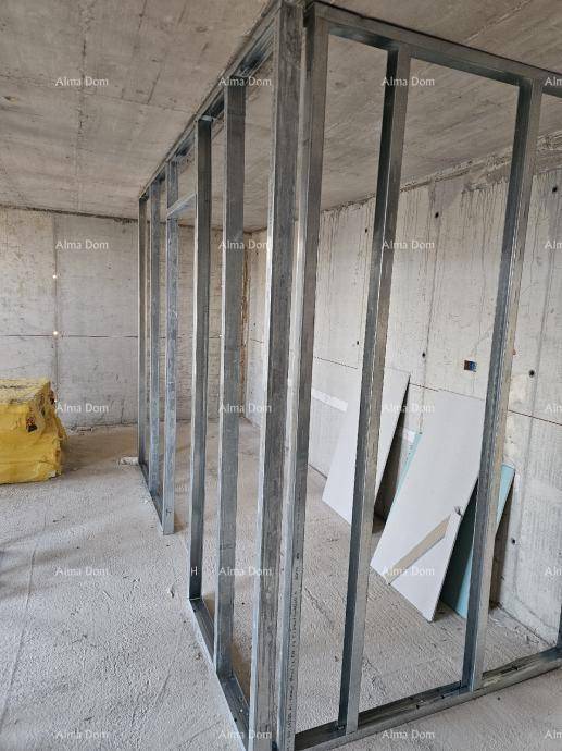 Rohbau eines Raumes mit Betonwänden, Metallrahmen für Wände und gestapelten Trockenbauplatten.