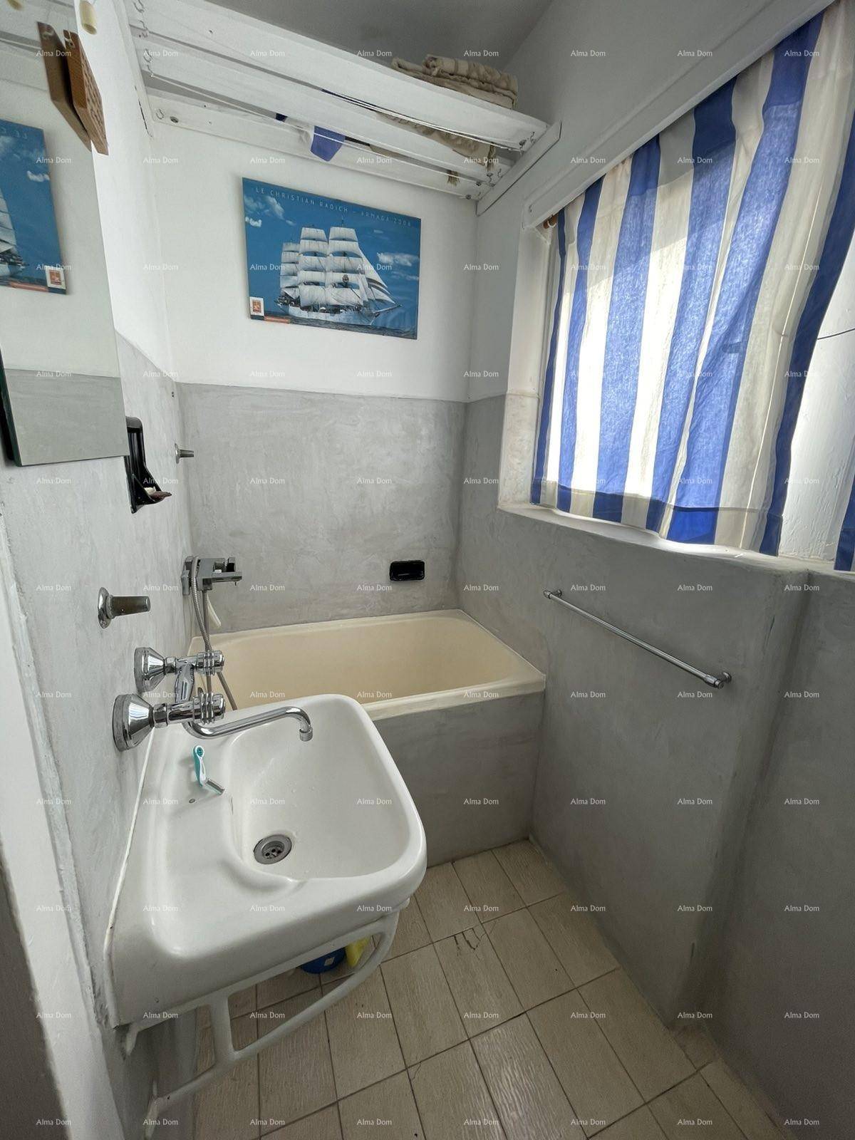 Kleines Badezimmer mit Badewanne, Waschbecken und Fenster, einfach und funktional.