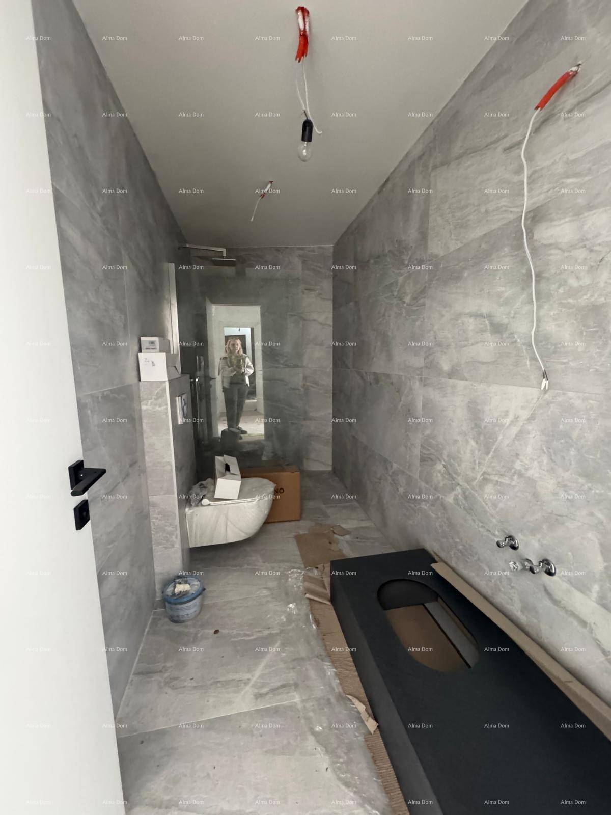 Modernes Badezimmer mit grauen Fliesen, wandhängendem WC und Platz für einen Waschtisch.