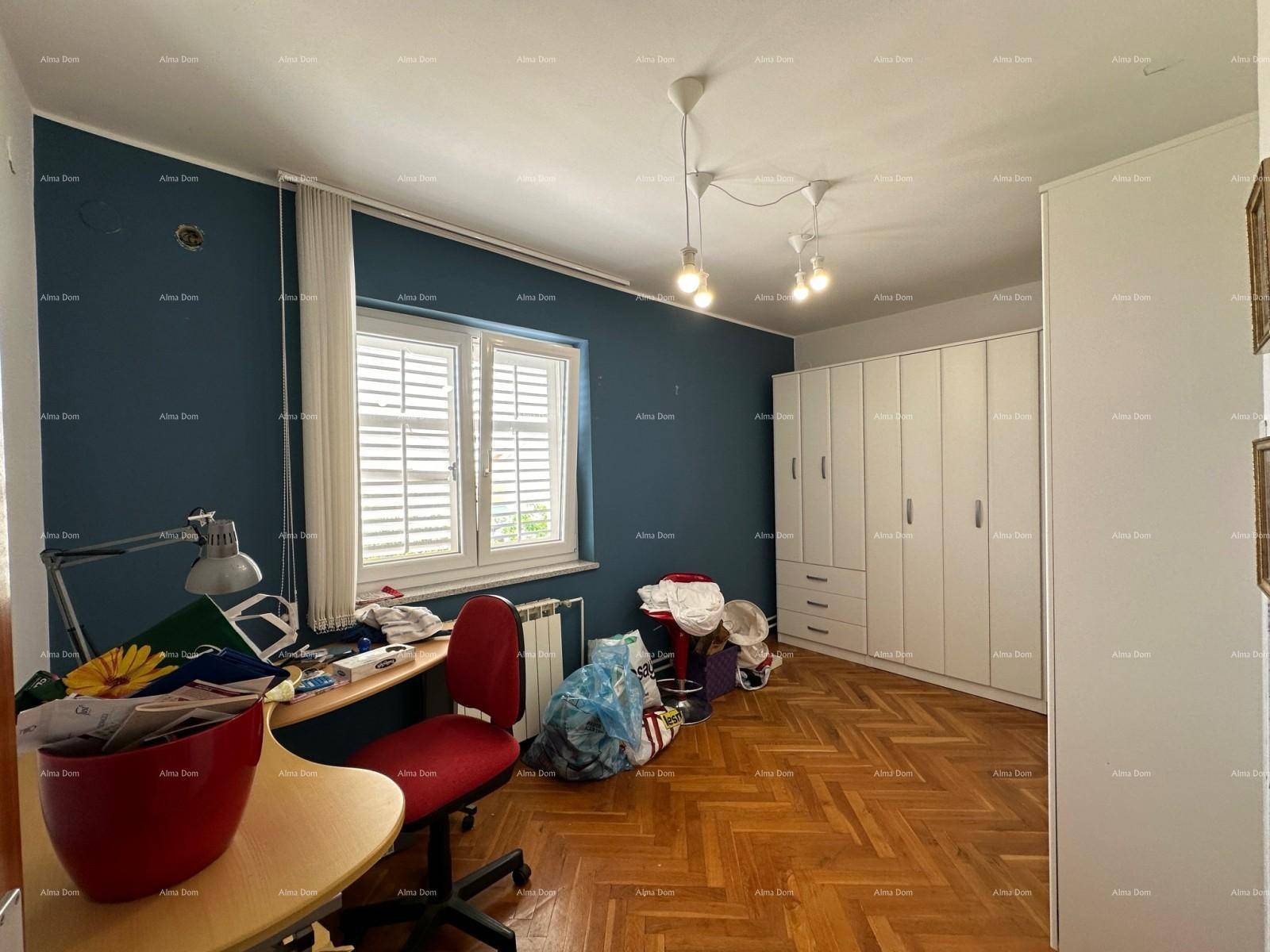 Schlafzimmer mit blauer Akzentwand, Fischgrätparkett und großem weißen Kleiderschrank.