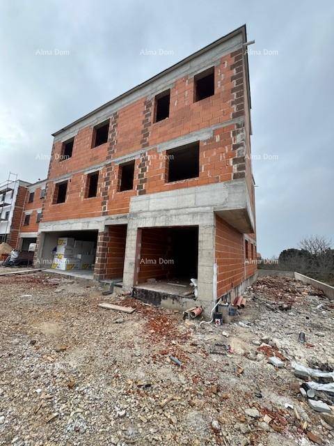 Neubau im Rohbauzustand mit Ziegelwänden und sichtbaren Betonelementen unter bewölktem Himmel.