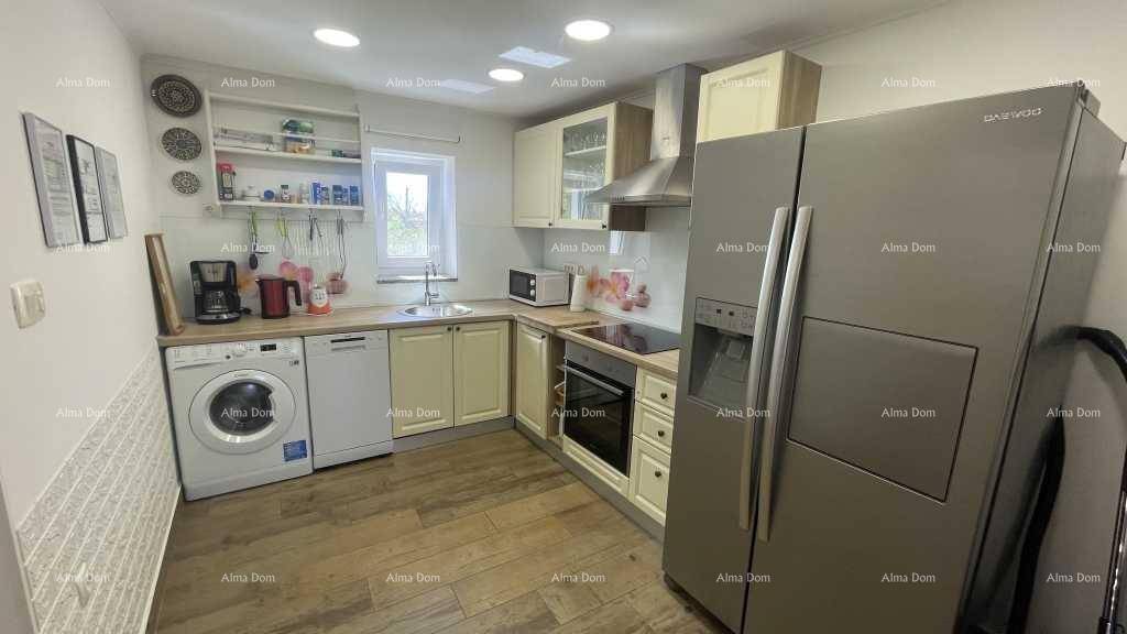 Funktionale Küche mit hellen Schränken, Holztheke und modernen Geräten, inklusive Waschmaschine.