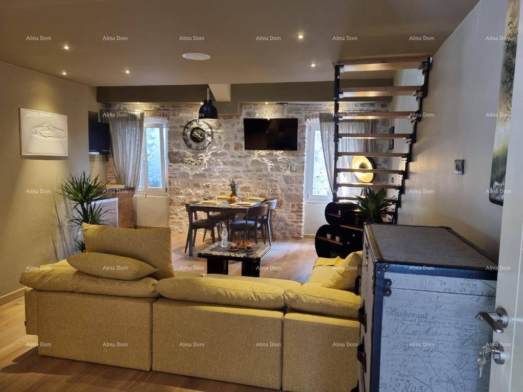 Offener Wohn- und Essbereich mit gelbem Sofa, Esstisch und rustikaler Steinwand, ergänzt durch eine moderne Treppe.