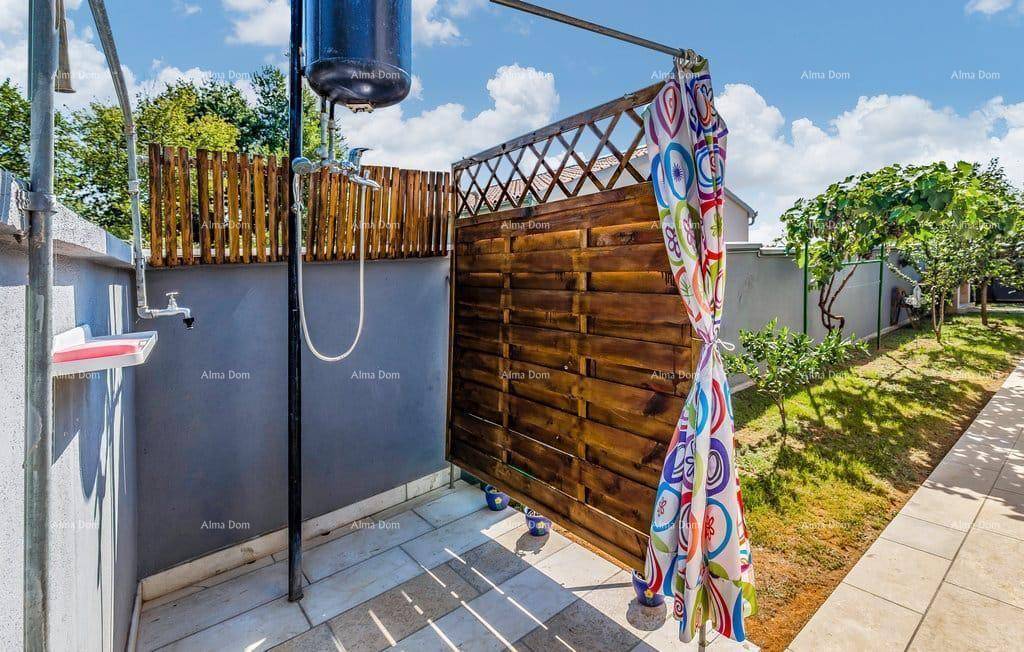 Außendusche im Gartenbereich mit Holzwand und farbenfrohem Duschvorhang für Erfrischung.