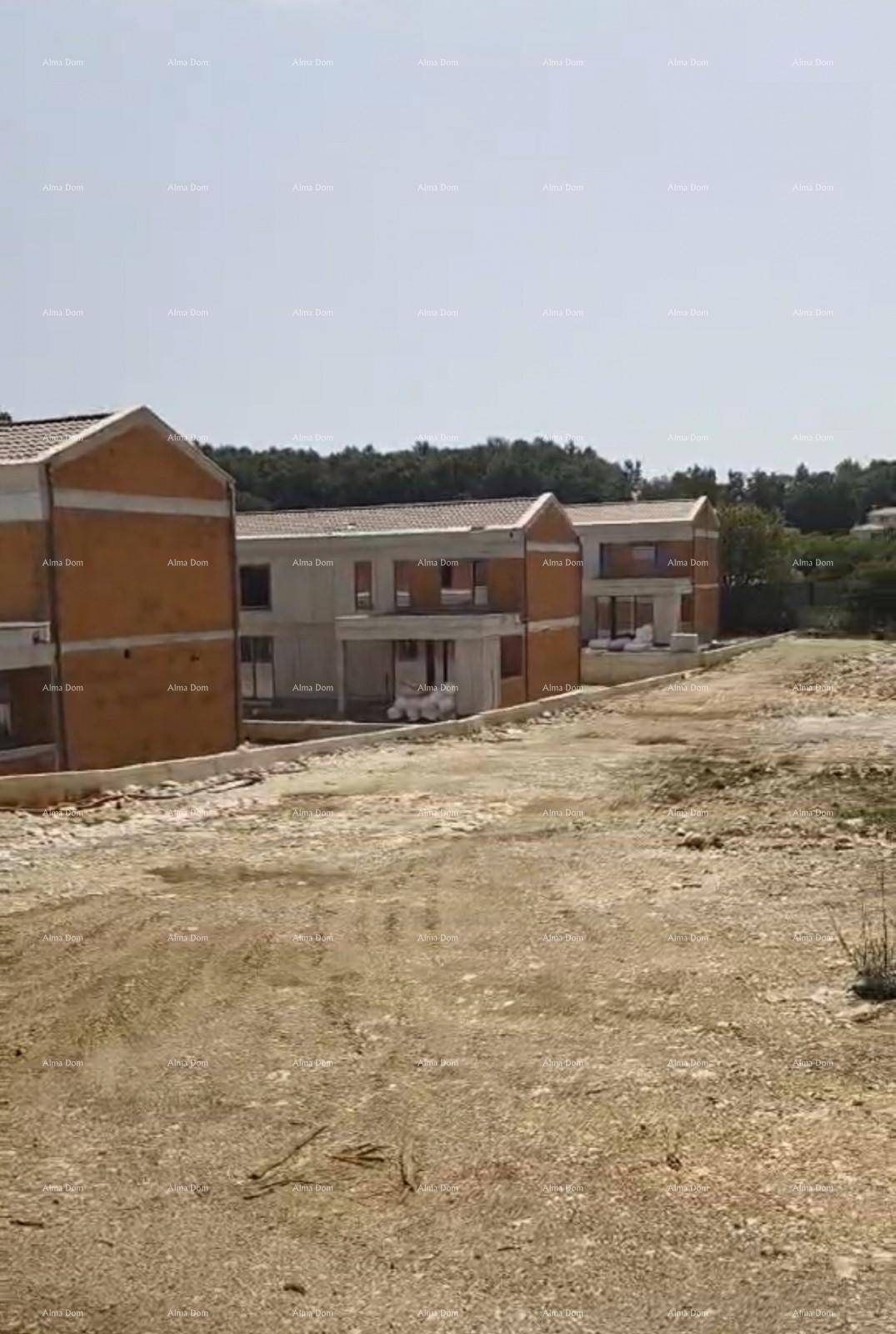 Reihe von Neubauvillen im Rohbauzustand, umgeben von ländlicher Landschaft.