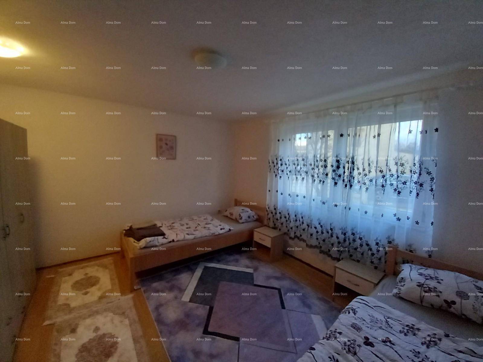 Helles Schlafzimmer mit zwei Einzelbetten, Holzfußboden und einem Fenster mit gemusterten Vorhängen.
