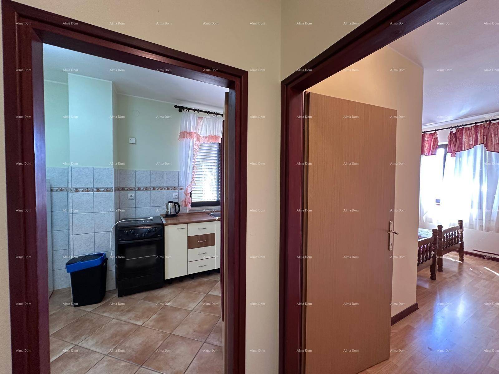 Flur mit Zugang zu einer Küche und einem weiteren Zimmer, mit Holztürrahmen.