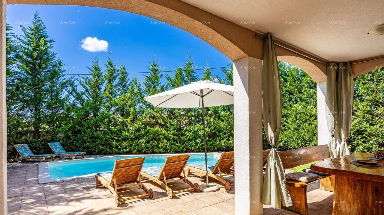 Blick von der überdachten Terrasse auf den Poolbereich mit Sonnenliegen und grüner Hecke.