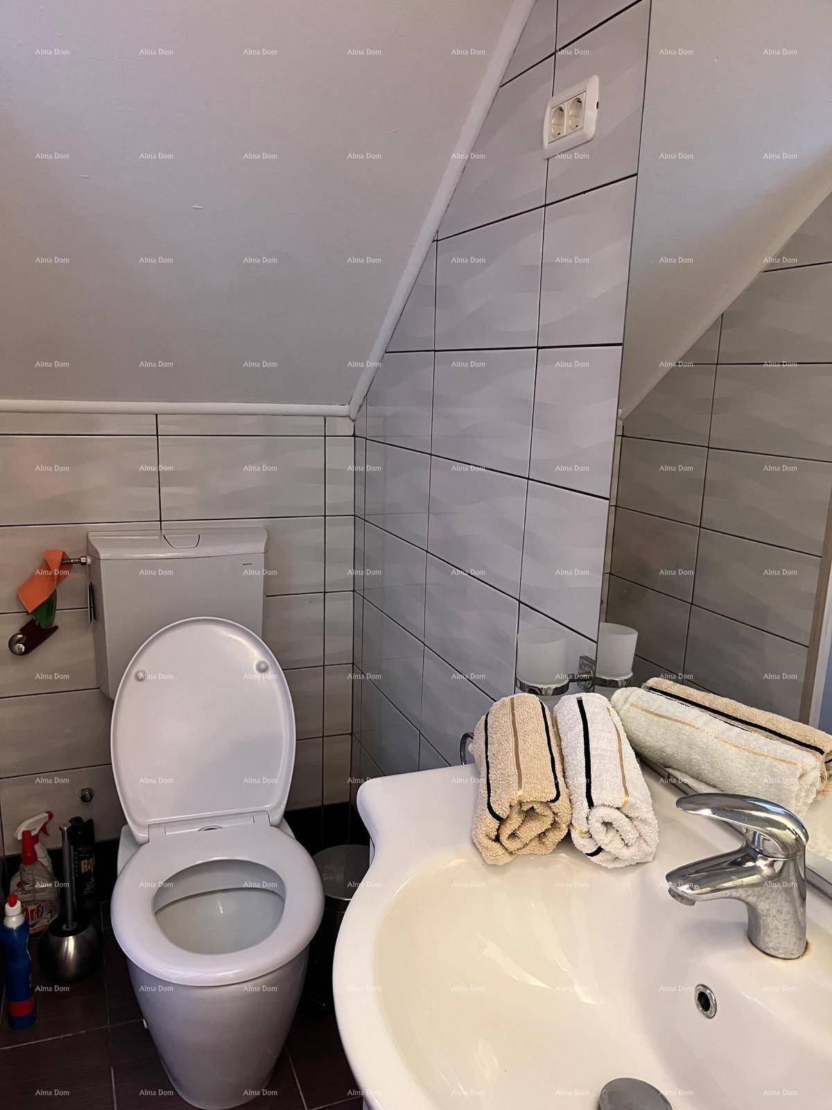 Badezimmer mit Toilette, Waschbecken und einer Dachschräge, die dem Raum Charakter verleiht.