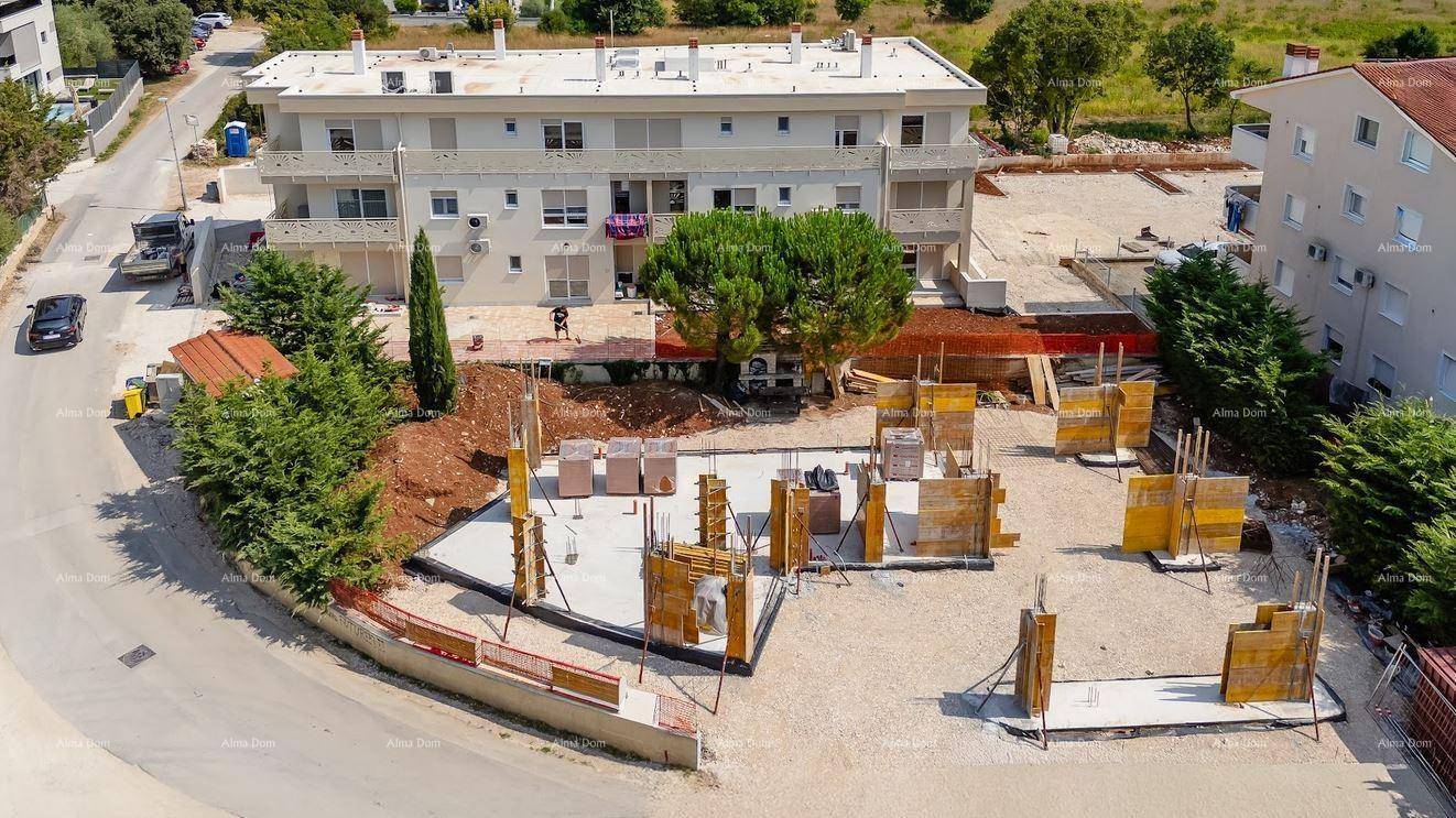 Luftaufnahme einer Baustelle mit Fundamentarbeiten und einem bestehenden Wohngebäude im Hintergrund.