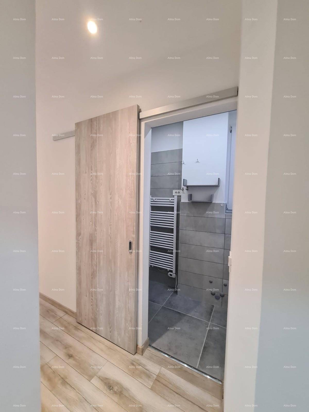 Heller Flur mit Holzoptik-Fliesenboden und Schiebetür zum modernen Badezimmer.
