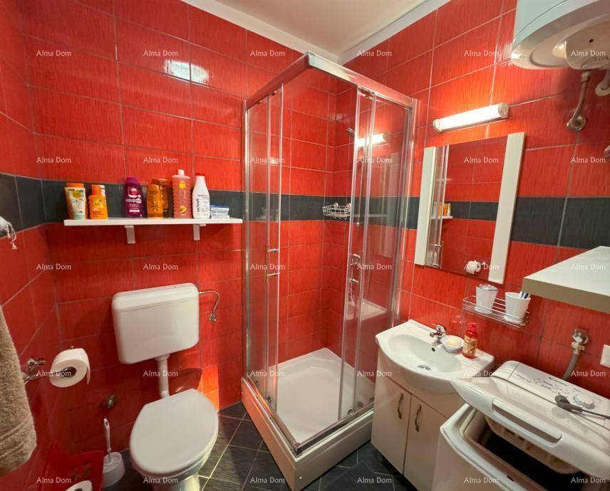 Funktionales Badezimmer mit roten Fliesen, Duschkabine, WC und Waschbecken mit Unterschrank.