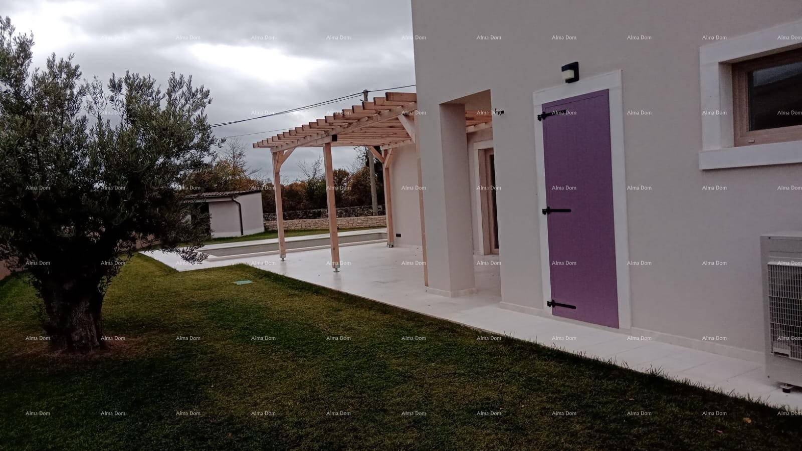 Hausfassade mit Pergola, Garten und Olivenbaum an einem bewölkten Tag.