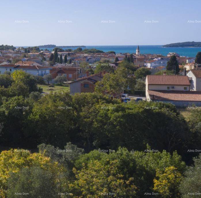 Weitblick über eine Küstenstadt mit einem Kirchturm, umgeben von üppigem Grün und dem Meer.