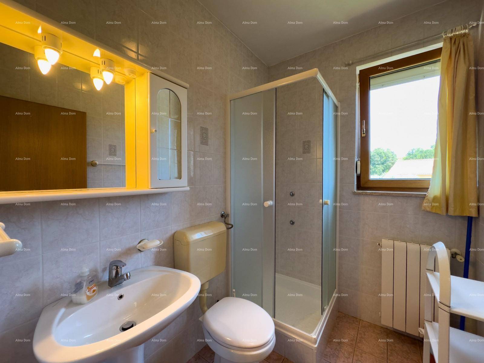 Badezimmer mit Dusche, Waschbecken, Toilette und Fenster, hell gefliest.