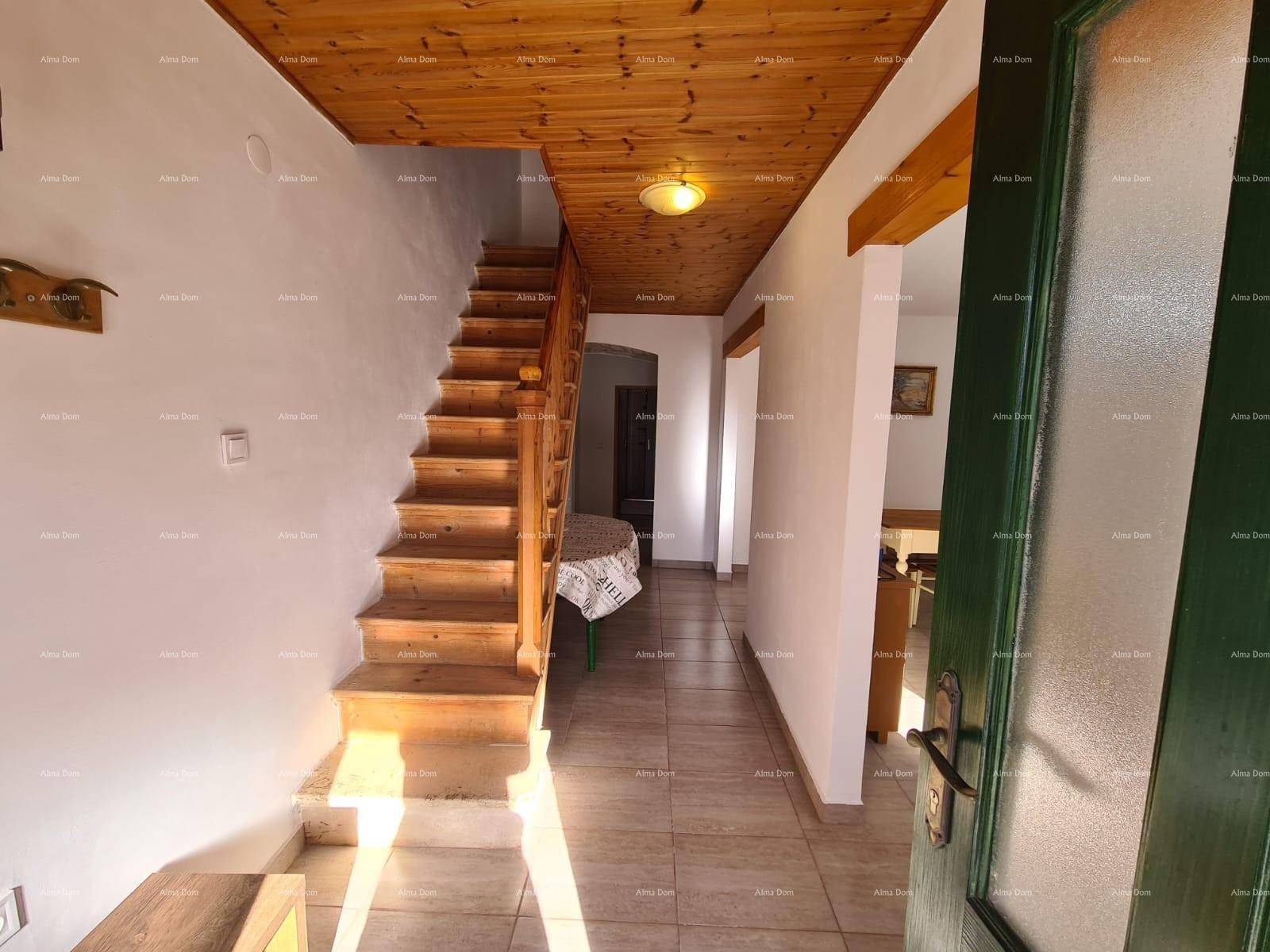 Geräumiger Eingangsbereich mit Holztreppe, Fliesenboden und grüner Eingangstür.
