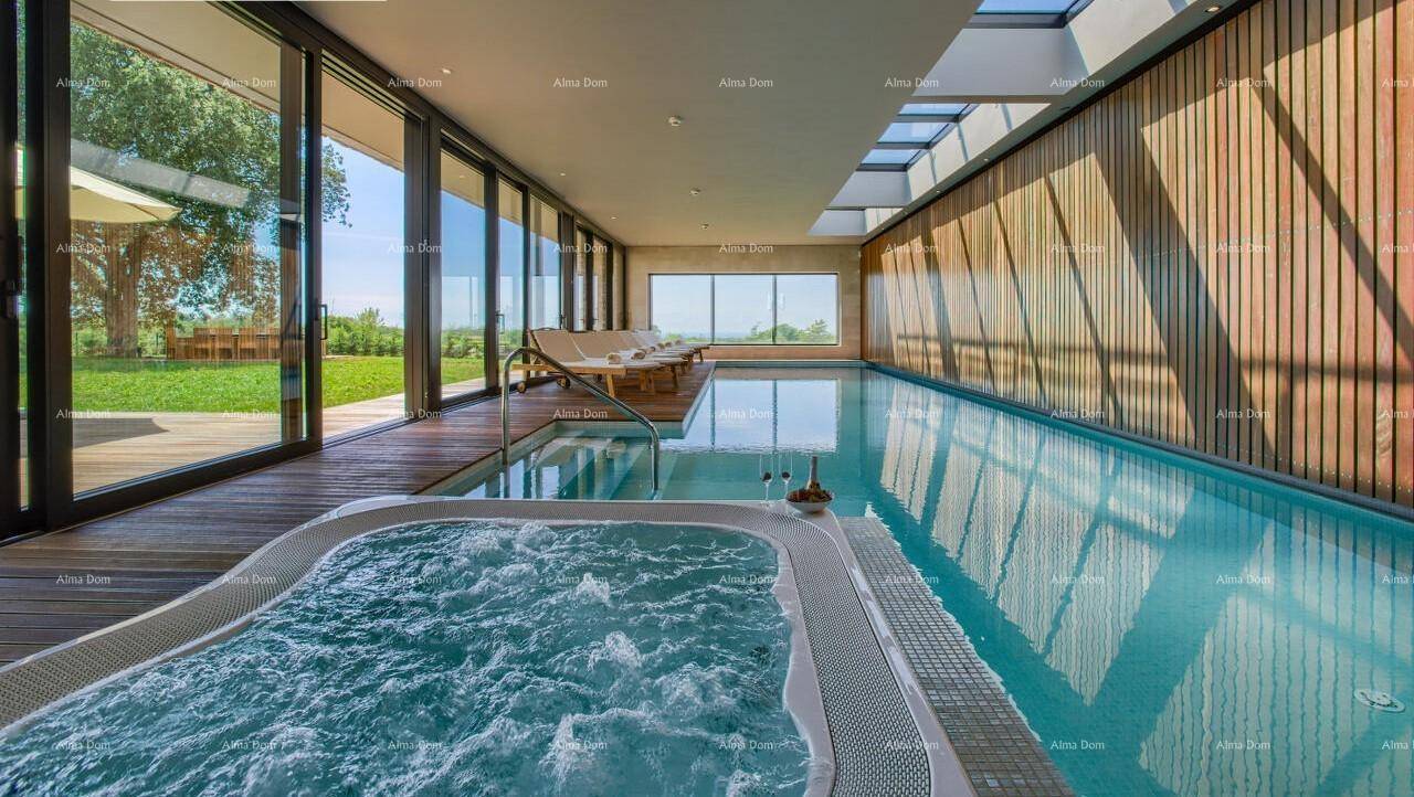 Lichtdurchfluteter Innenpool mit sprudelndem Whirlpool und weitem Blick auf die grüne Landschaft.