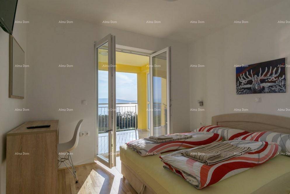 Schlafzimmer mit Doppelbett, Holzboden und direktem Zugang zu einem Balkon mit Meerblick.
