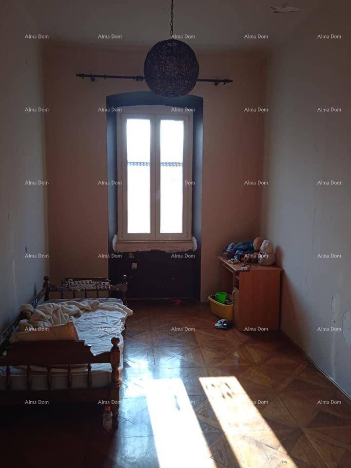 Schlafzimmer mit Parkettboden, einem Einzelbett und einem Fenster, das den Raum mit Sonnenlicht erhellt.