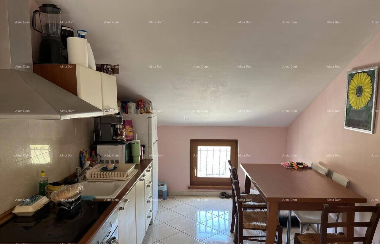 Dachgeschossküche mit Essbereich, Einbauschränken und einem Fenster, das Tageslicht spendet.