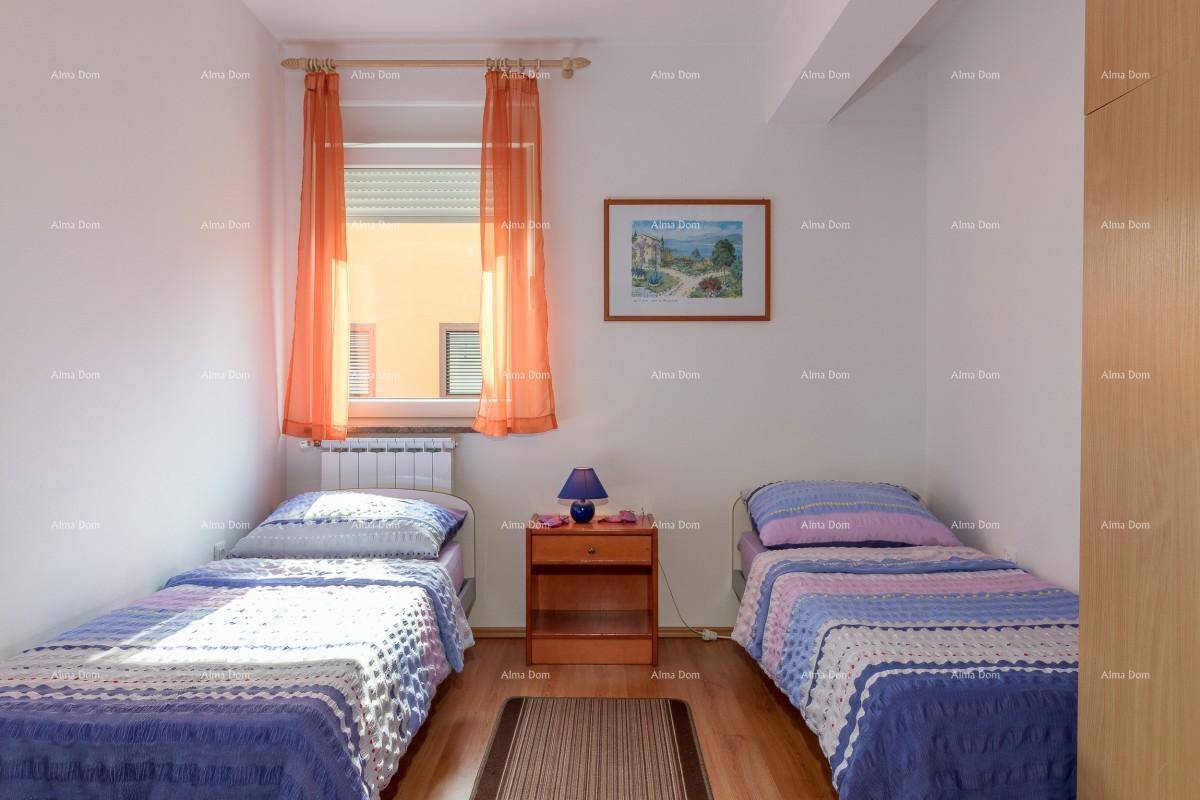 Helles Schlafzimmer mit zwei Einzelbetten, Holzfußboden und einem Fenster mit orangefarbenen Vorhängen.