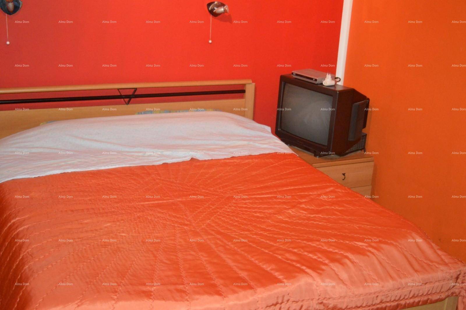 Schlafzimmer mit leuchtend orangen Wänden, Doppelbett und einem kleinen Fernseher.