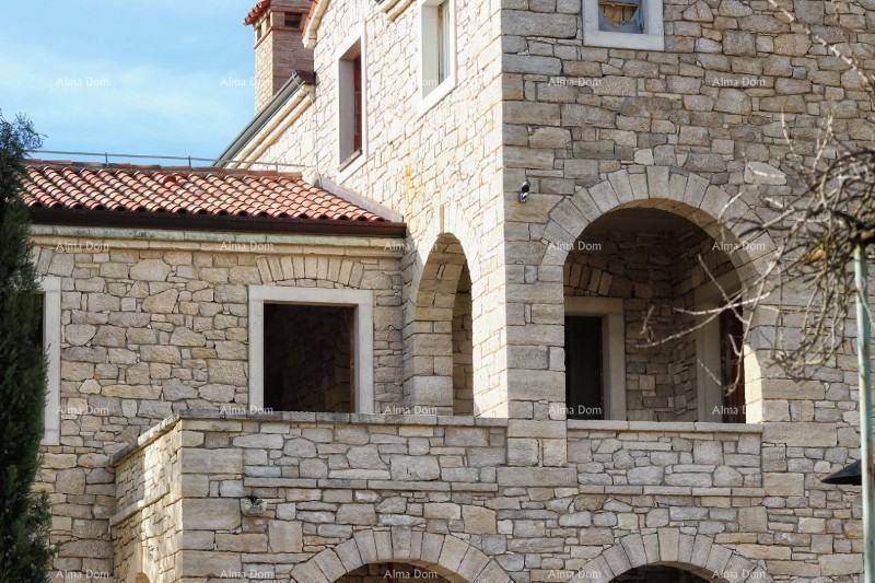 Fassadendetail des Steinhauses mit Rundbögen, Fenstern und traditionellem Dach.