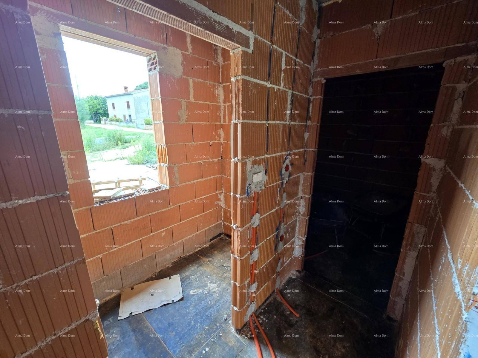Innenraum im Rohbau mit Ziegelwänden, Fensteröffnung und vorbereiteten Elektroinstallationen.