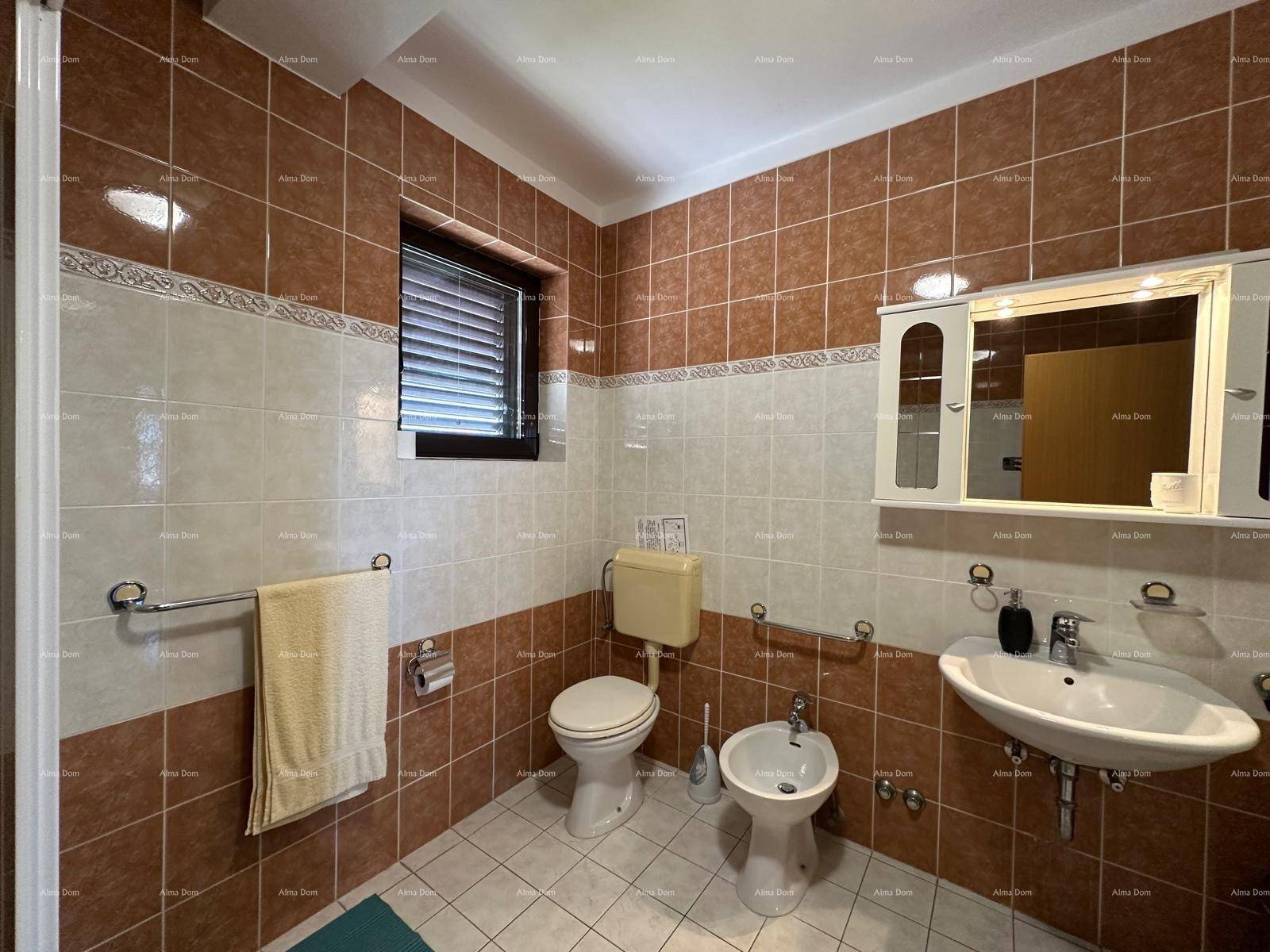 Badezimmer mit braun-weißen Fliesen, WC, Bidet und Waschbecken mit Spiegelschrank.