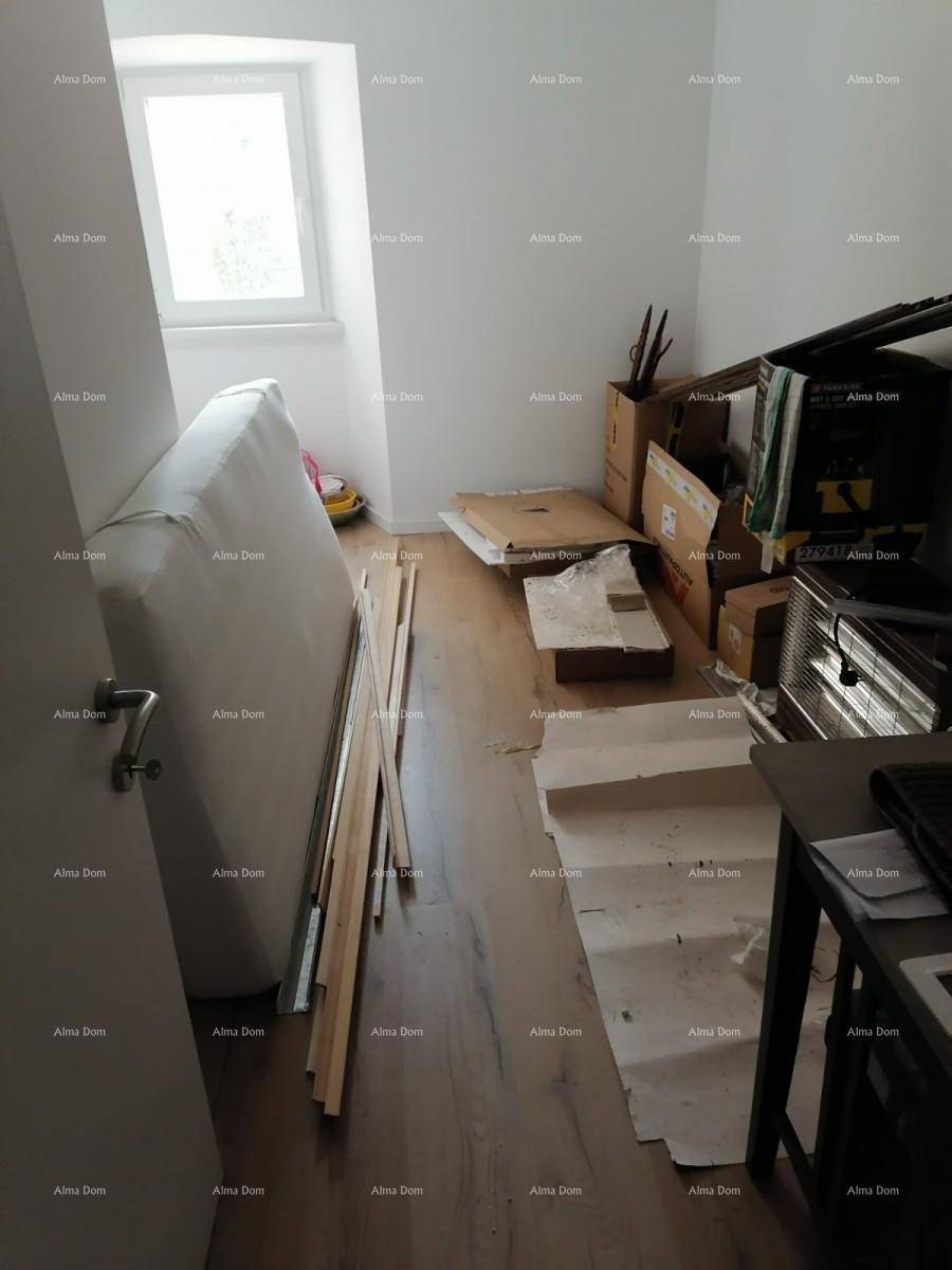 Helles Schlafzimmer mit Fenster und Holzboden, derzeit als Lagerraum genutzt.