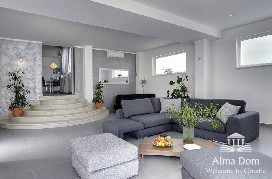 Modernes Wohnzimmer mit bequemer grauer Couch, stilvoller Dekoration und Treppenaufgang.