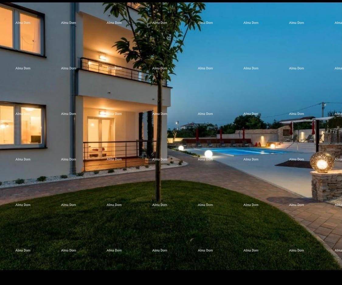 Nachtaufnahme des Gebäudes mit beleuchtetem Gartenbereich und dem schimmernden Pool im Hintergrund.