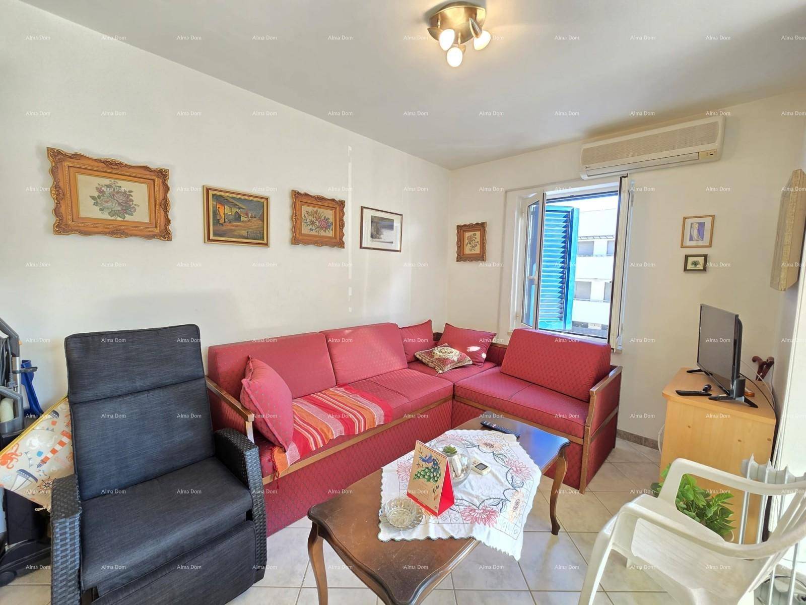 Gemütlicher Wohnbereich mit rotem Sofa, Klimaanlage und Fenster mit blauen Fensterläden.